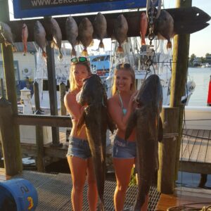 Two Blond Women Holding Two Big Fishes by Hook