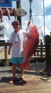 A Boy Holding a Big Orange Fish by a Hook