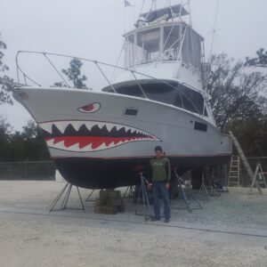 A Man Standings Beside a Boat With Shark Mouth Paint