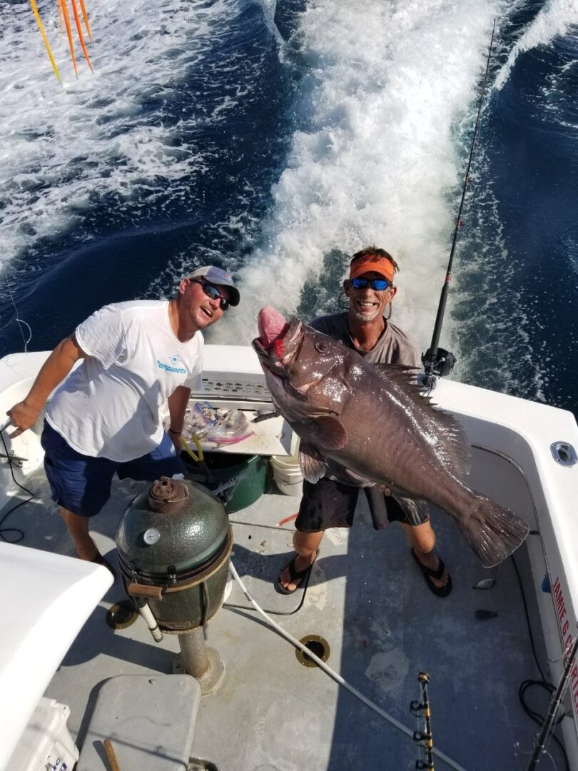 Two Men With a Grey and White Color Fish